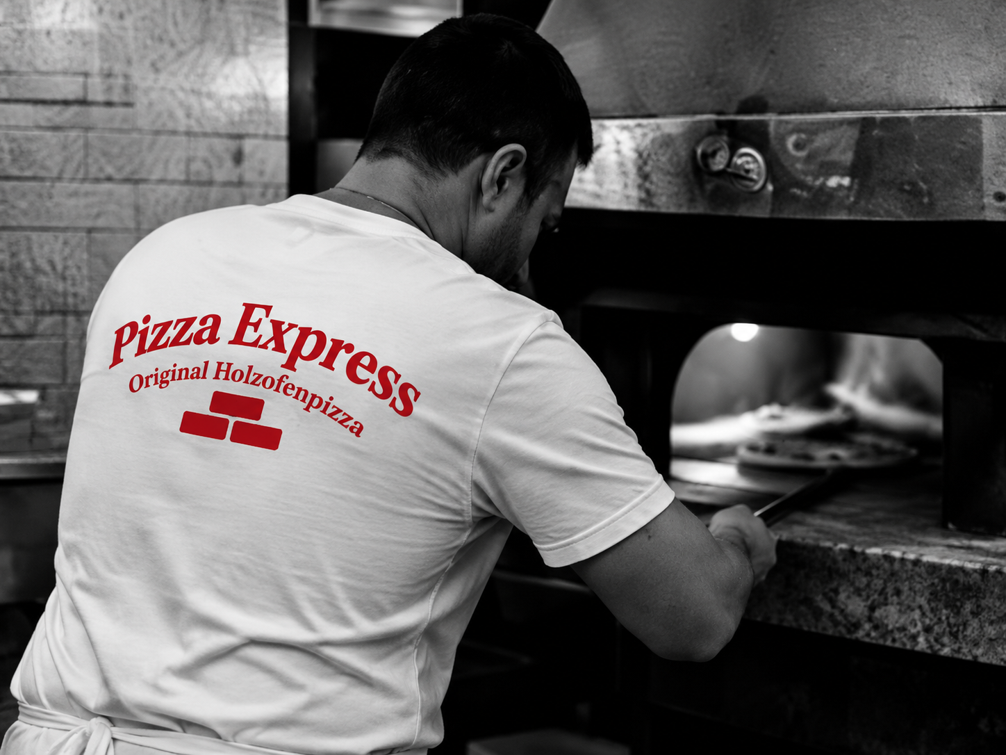 Pizzabäcker von Pizza Express bei der Arbeit am Holzofen.